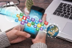 Um celular na mão de uma pessoa com vários ícones de redes sociais interligados.