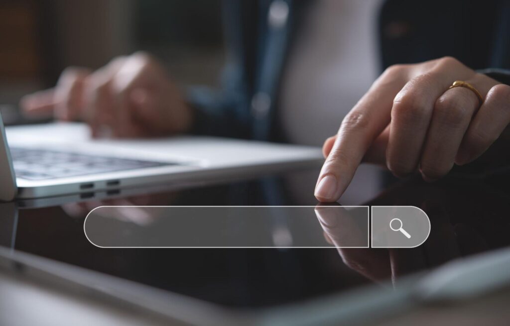 Uma pessoa usando um computador e uma barra de busca na imagem.